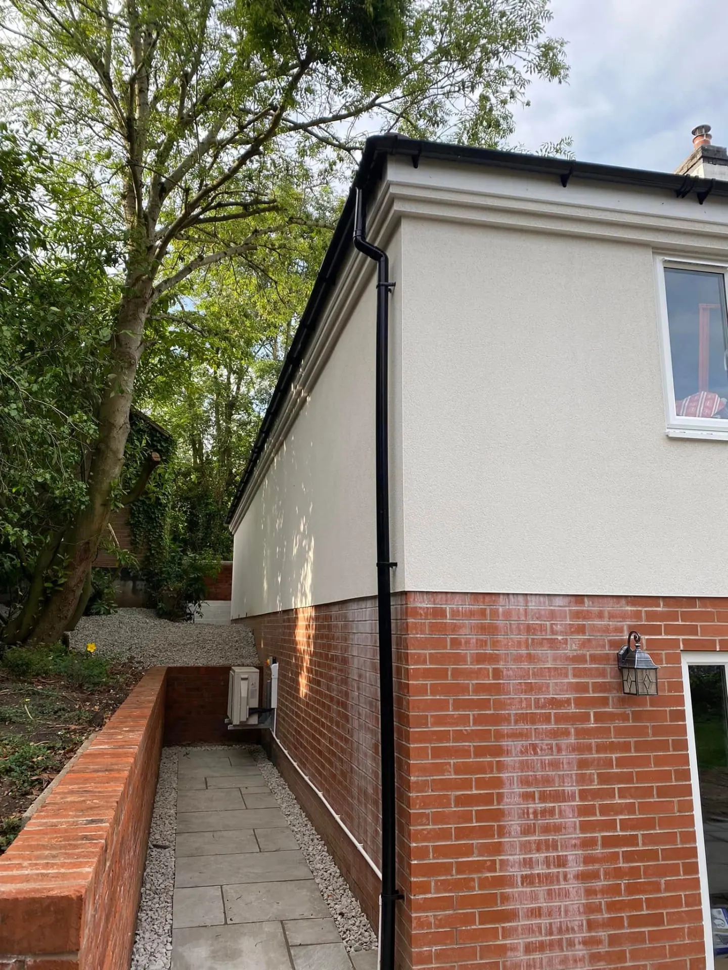 Side elevation of the Whiteoaks annexe showing the rendered upper storey, brick plinth and discreetly sited air conditioning unit