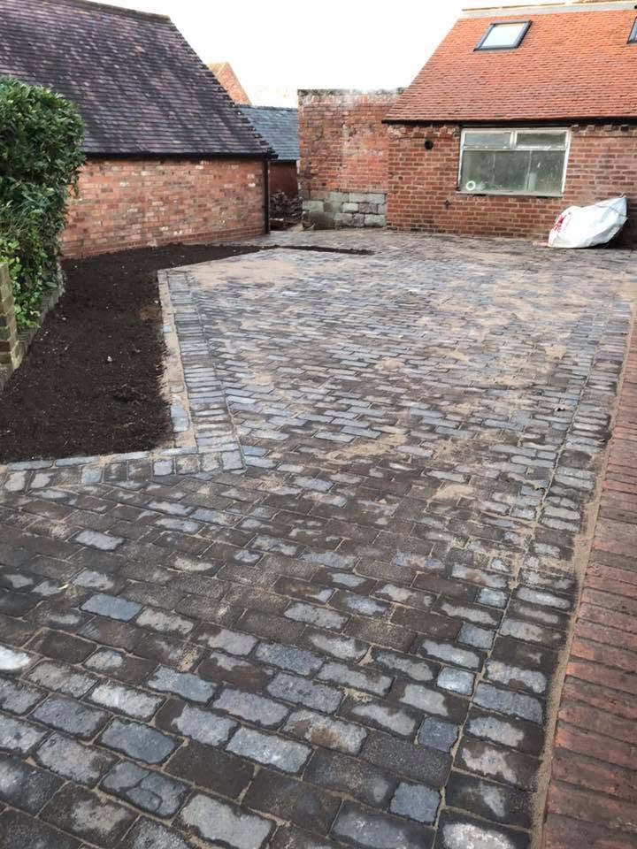 Newly laid reclaimed cobble and sett courtyard at the listed farmhouse, with sett banding borders and prepared planting beds