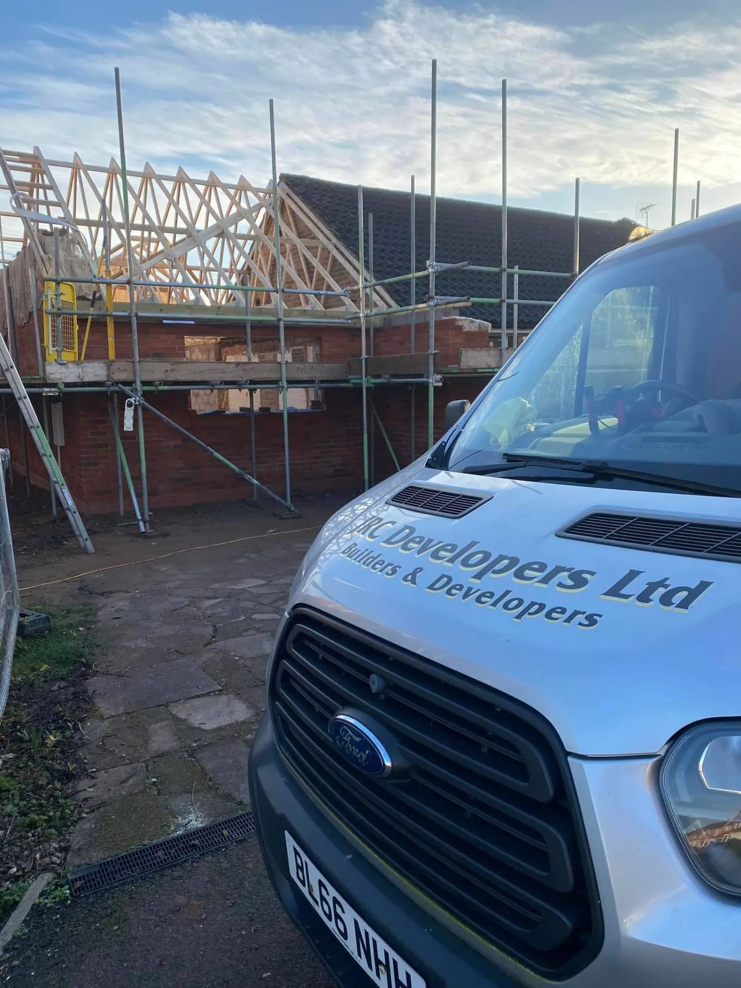 Full scaffold across White Gates during roof carpentry stage with the JRC Developers Ltd van in the foreground and hand-cut timber trusses going up