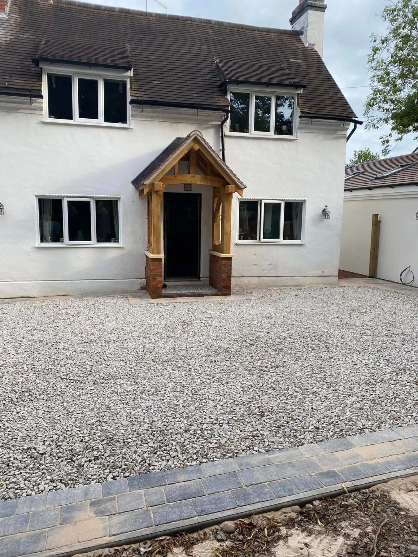 Completed oak framed porch at Whiteoaks with clay tiled roof and the new gravel driveway with block paved edging in front
