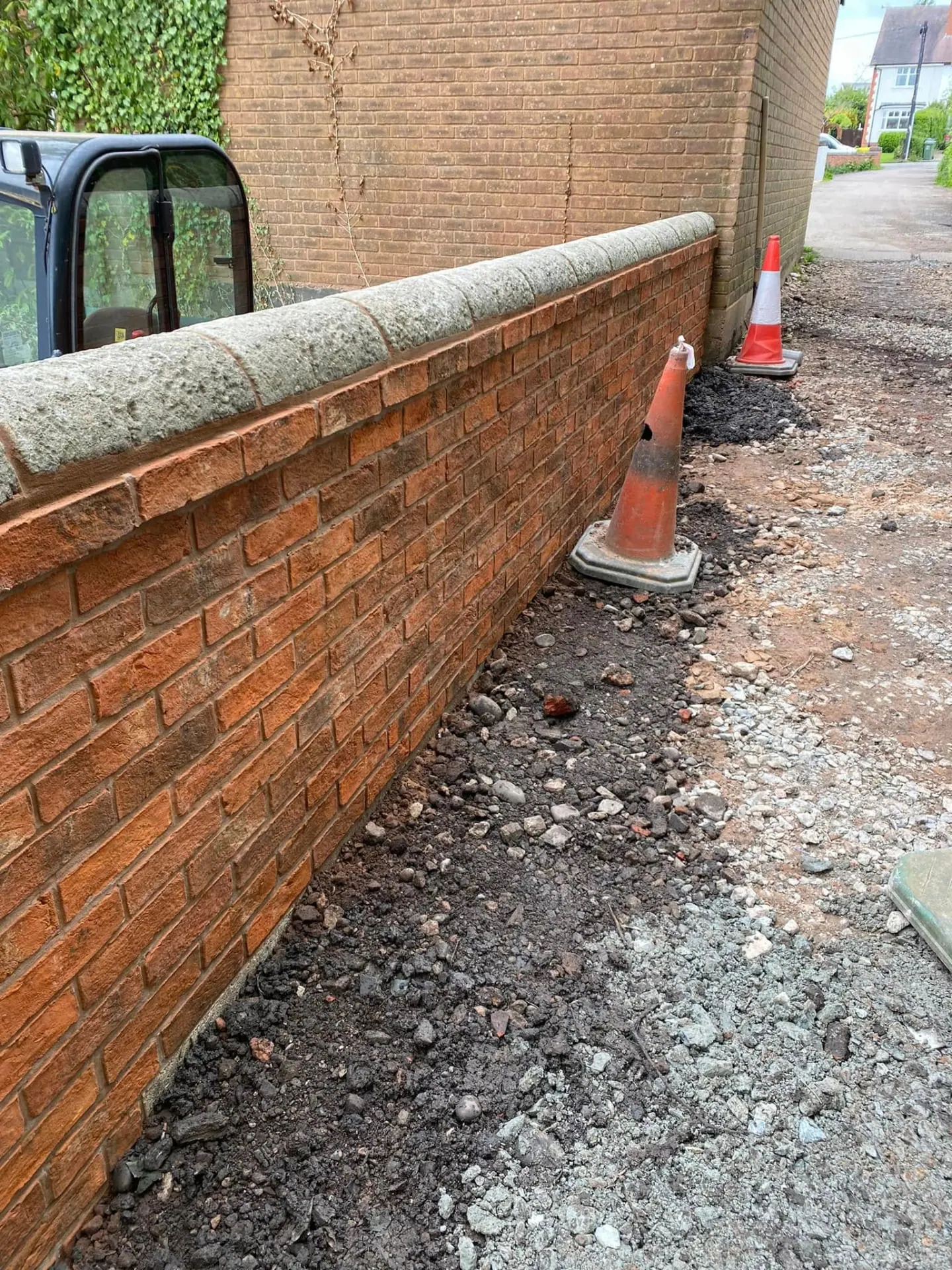 The full run of the new brick boundary wall along the driveway edge at Whiteoaks with traffic cones during construction